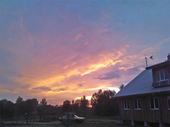 Saimniecības ēkas projekta realizācijas gaita un foto ar vēja ģeneratoru saulrietā