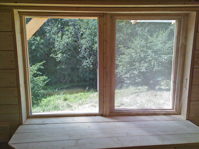 Skats uz upi caur sīkmājas logu